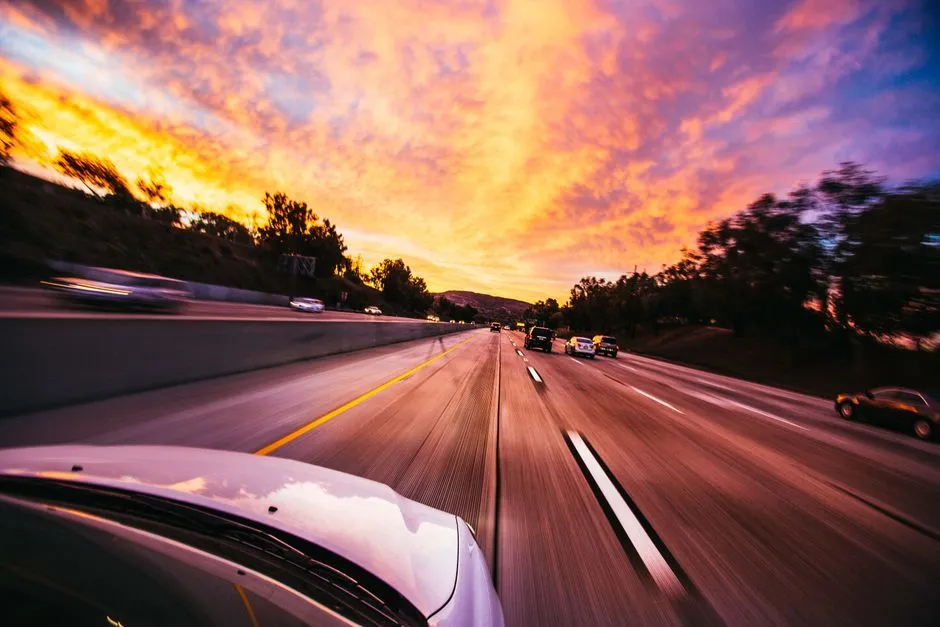 Car driving down a highway at sunset on a road trip